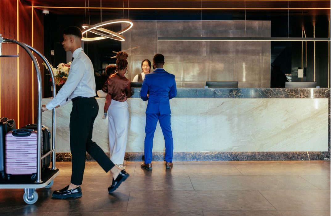 Guests arriving at the hotel front desk to drop off their luggage.